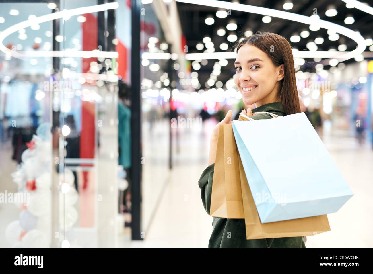 Portrait of happy pretty girl with shopping bags on shoulder standing ...