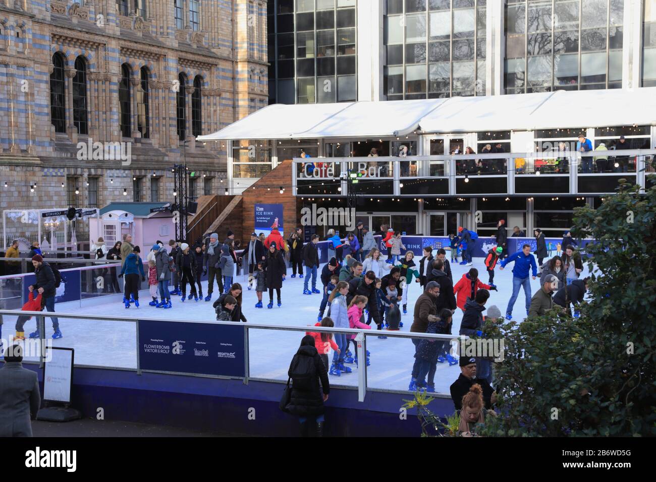 People ice skate during the Christmas and winter holiday activities outside a café and bar, and the Natural History Museum in Kensington, London, UK. Stock Photo