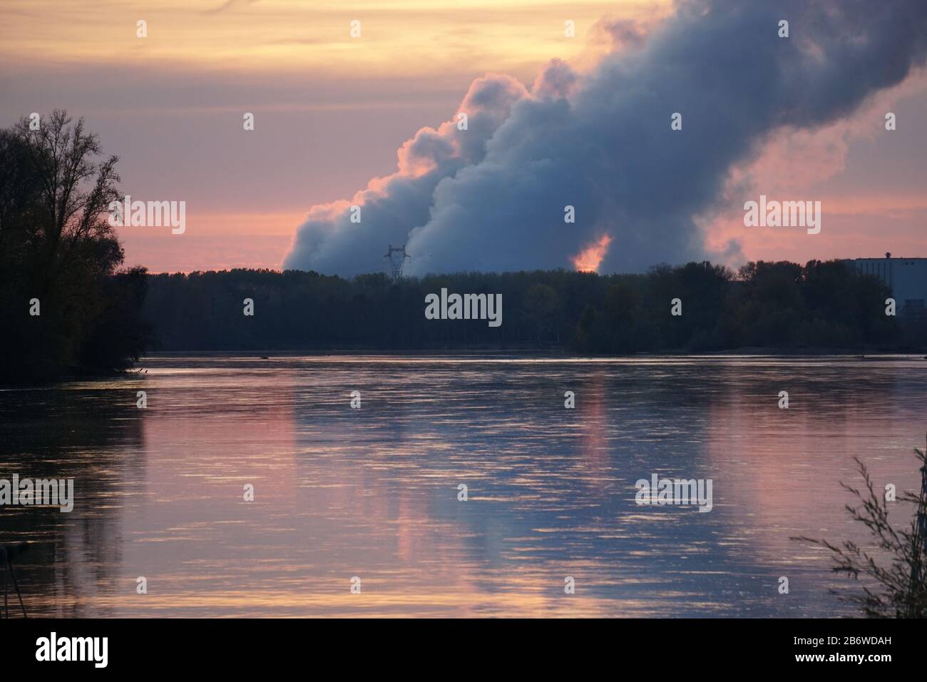 sunset on the rising steam from the nuclear power plant on the river Loire, France with reflection in the water Stock Photo