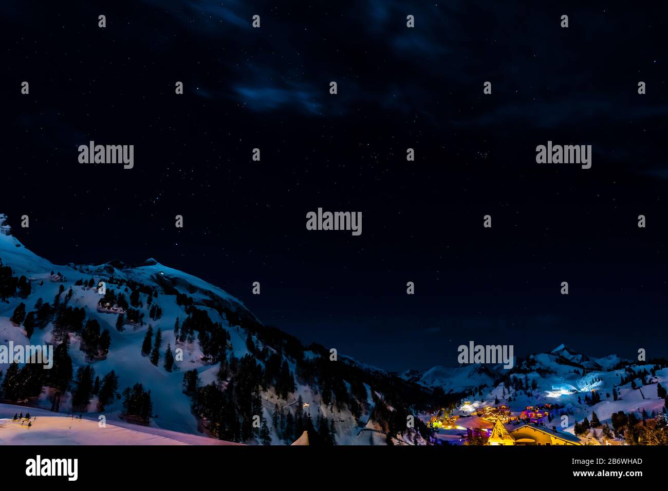 Stars (Orion's Belt and the Pleiades) and lights over Obertauern, Austria Stock Photo