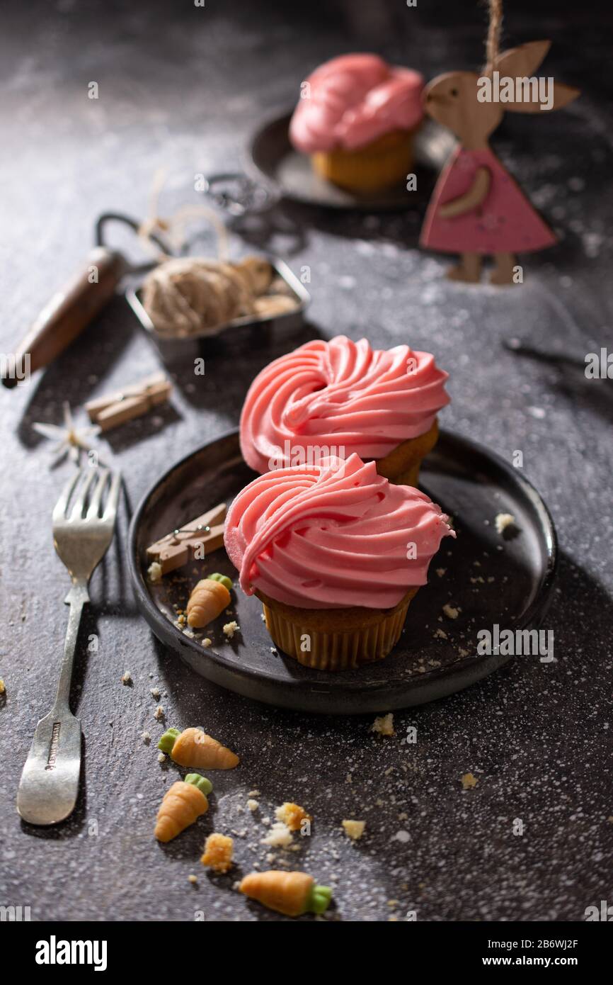 Cupcakes with fruit flavor cream.Easter dessert.Wooden bunny on the table.Delicious food. Stock Photo