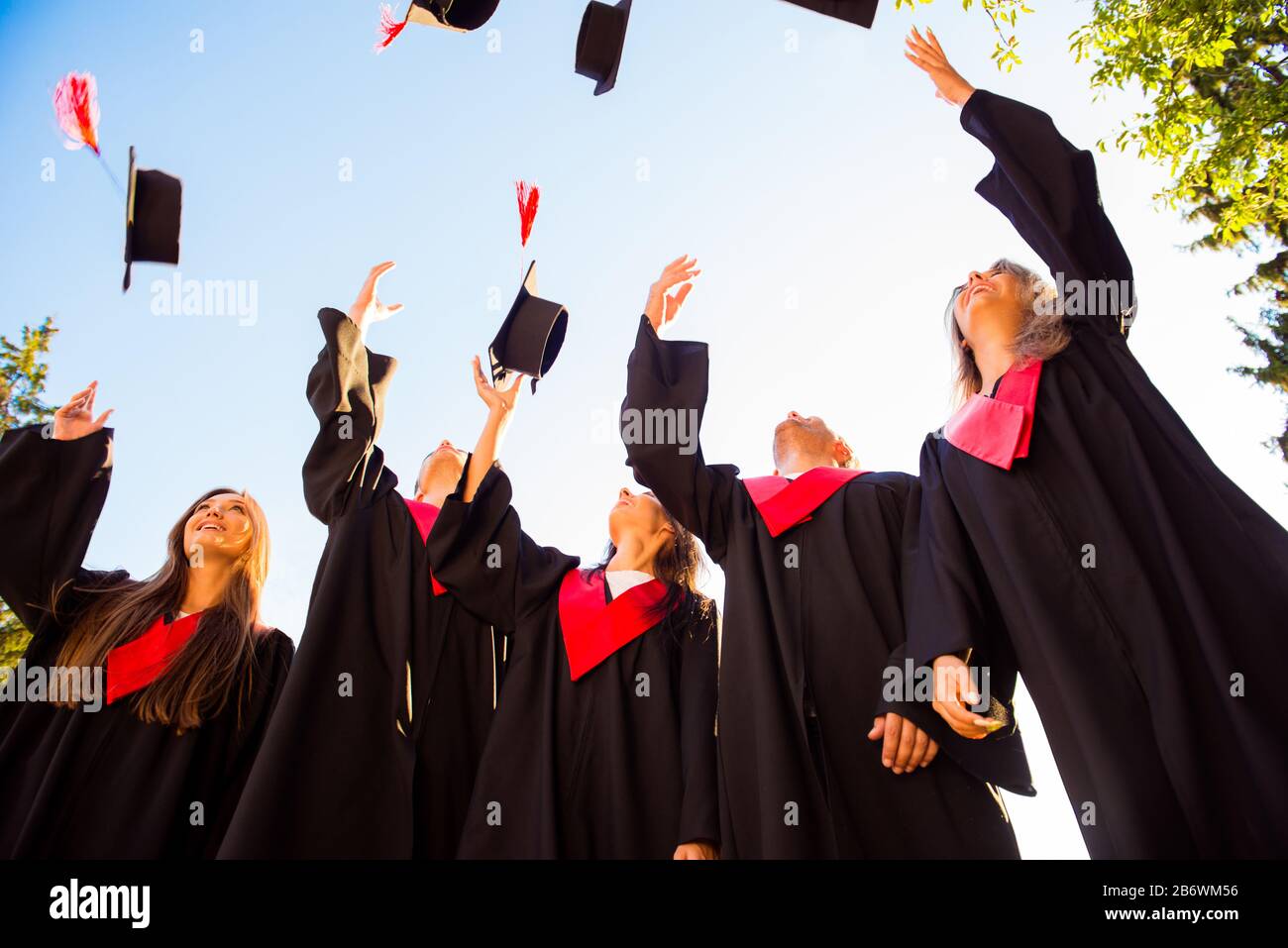 Happy group of graduated young students throwing hats in the air Stock