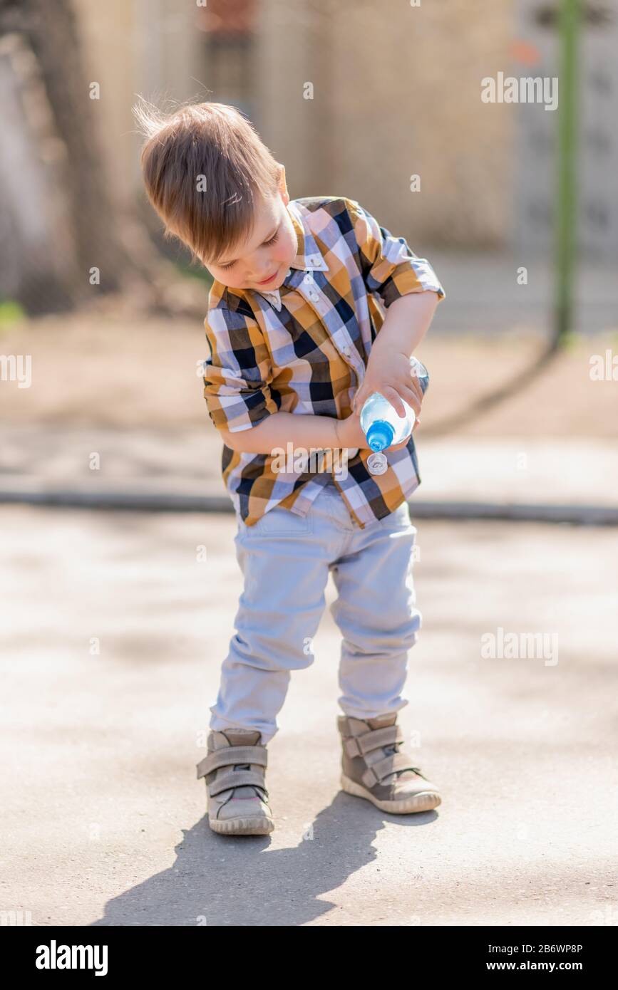 https://c8.alamy.com/comp/2B6WP8P/beautiful-kid-pours-water-from-a-bottle-on-the-pavement-2B6WP8P.jpg