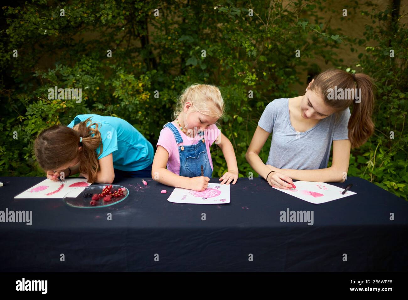 Children investigating food. Series: Painting fruit, in this case red berries. Learning according to the Reggio Pedagogy principle, playful understanding and discovery. Germany. Stock Photo
