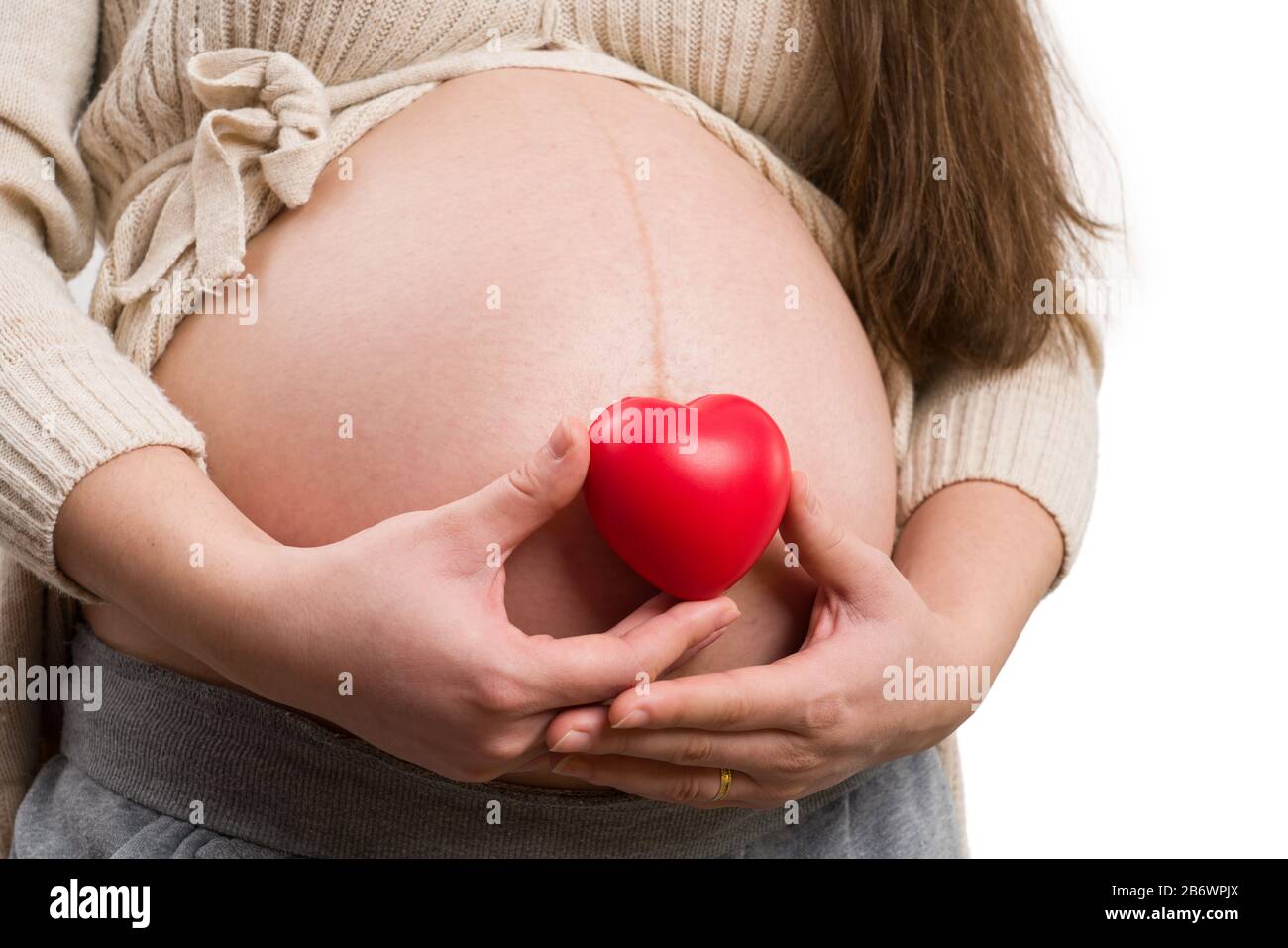 Close-up of future mom holding heart toy as love concept isolated on white background Stock Photo