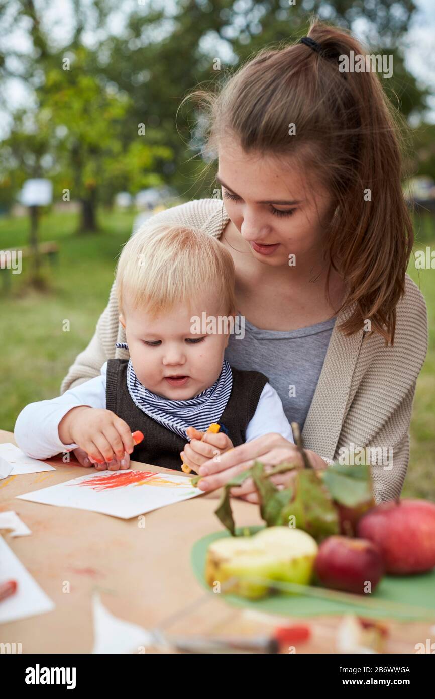 Children investigating food. Series: Apple Meadow Festival. A toddler drawing an apple. Learning according to the Reggio Pedagogy principle, playful understanding and discovery. Germany. Stock Photo