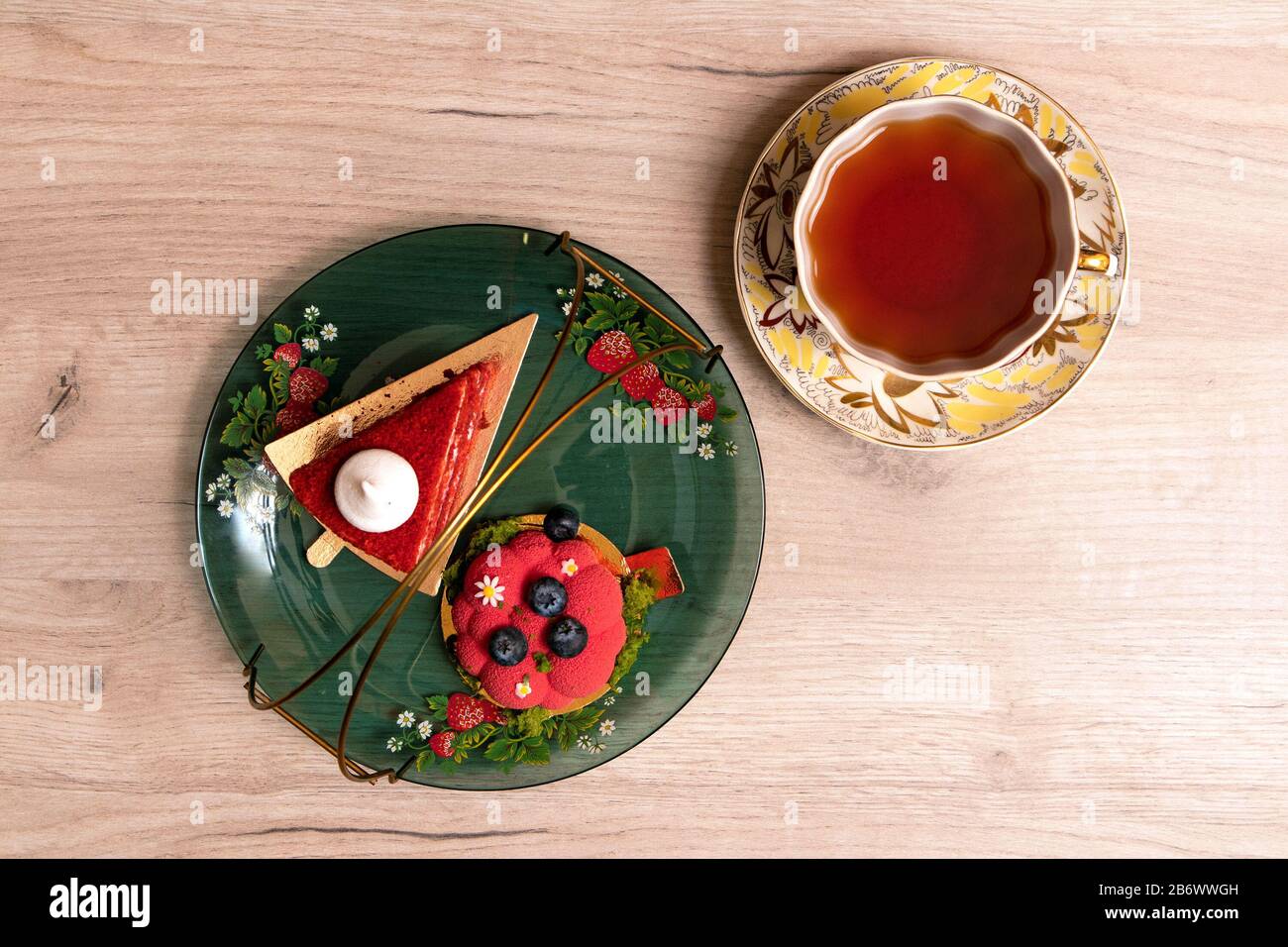 Two appetizing delicious red cakes on a glass plate with cup of tea nearby, top view Stock Photo