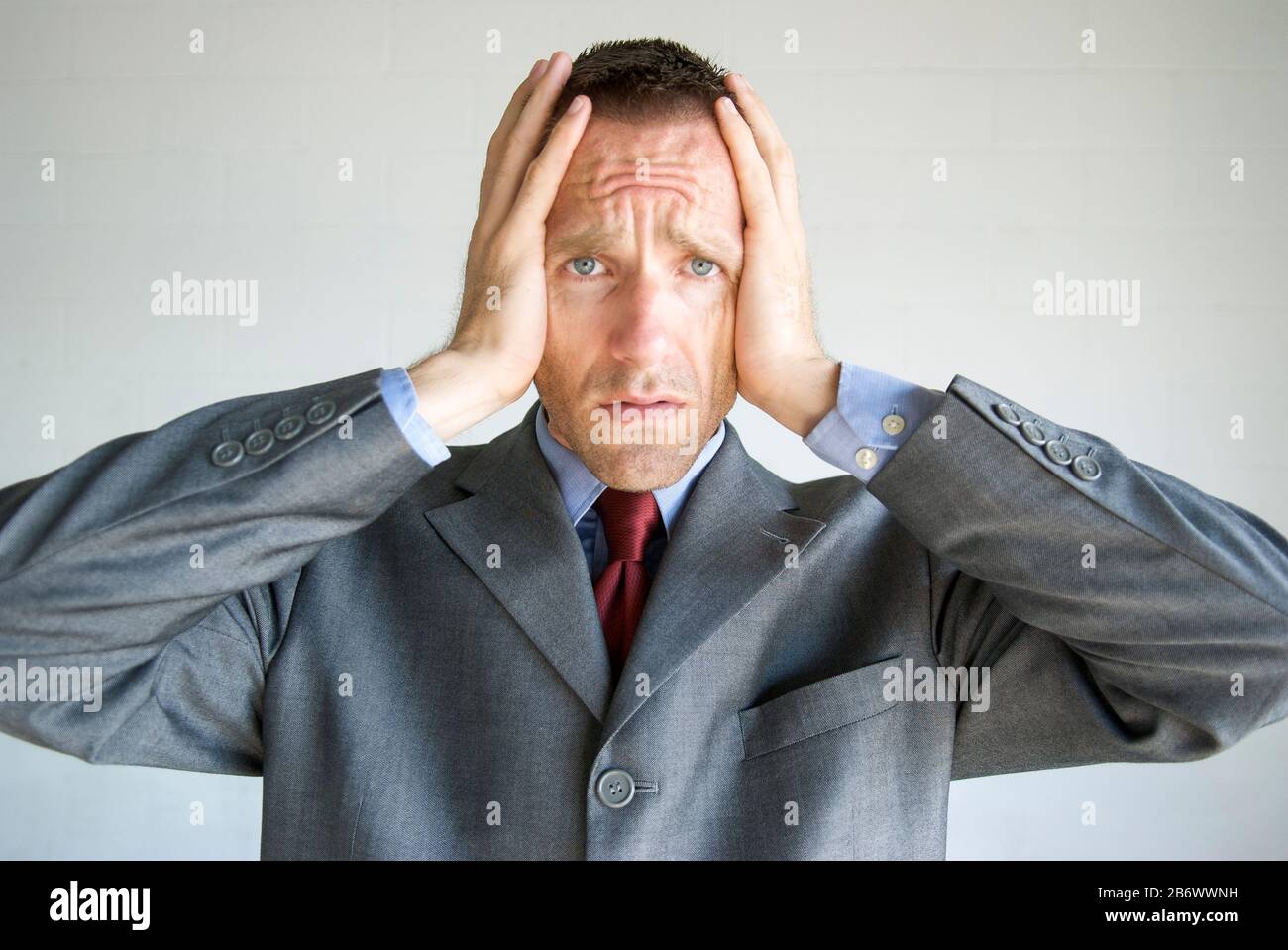 Worried businessman holding his head in his hands with an expression of ...