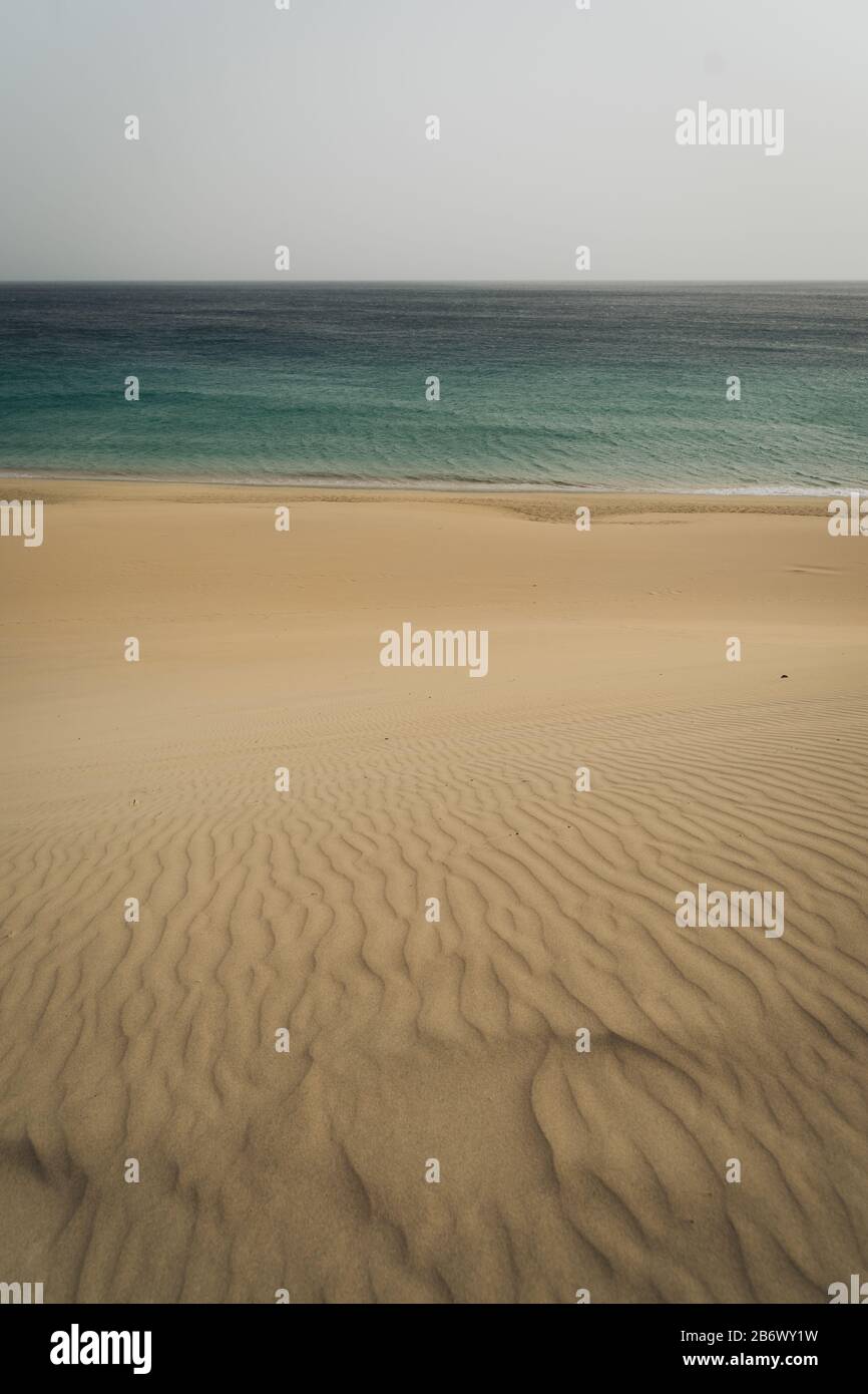 Very calm shot of beach with textured sand hills and blue water Stock Photo