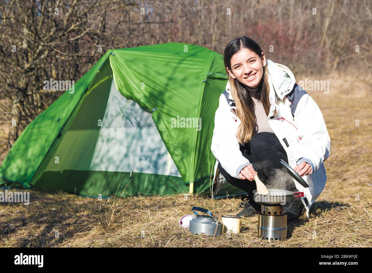 cheerful woman camping alone cooking in front of her tent. time for  outdoors Stock Photo - Alamy