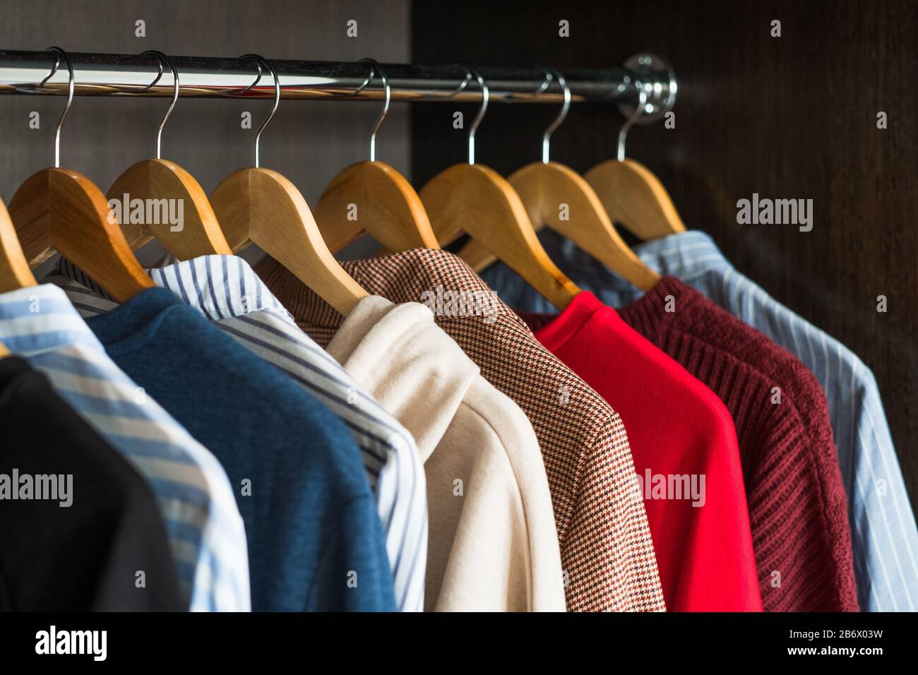 Hangers with different clothes in wardrobe closet. Stock Photo