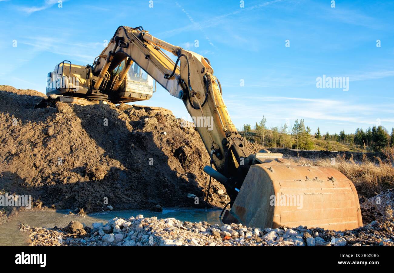 Yellow excavator on a road construction site against blue sky Stock ...