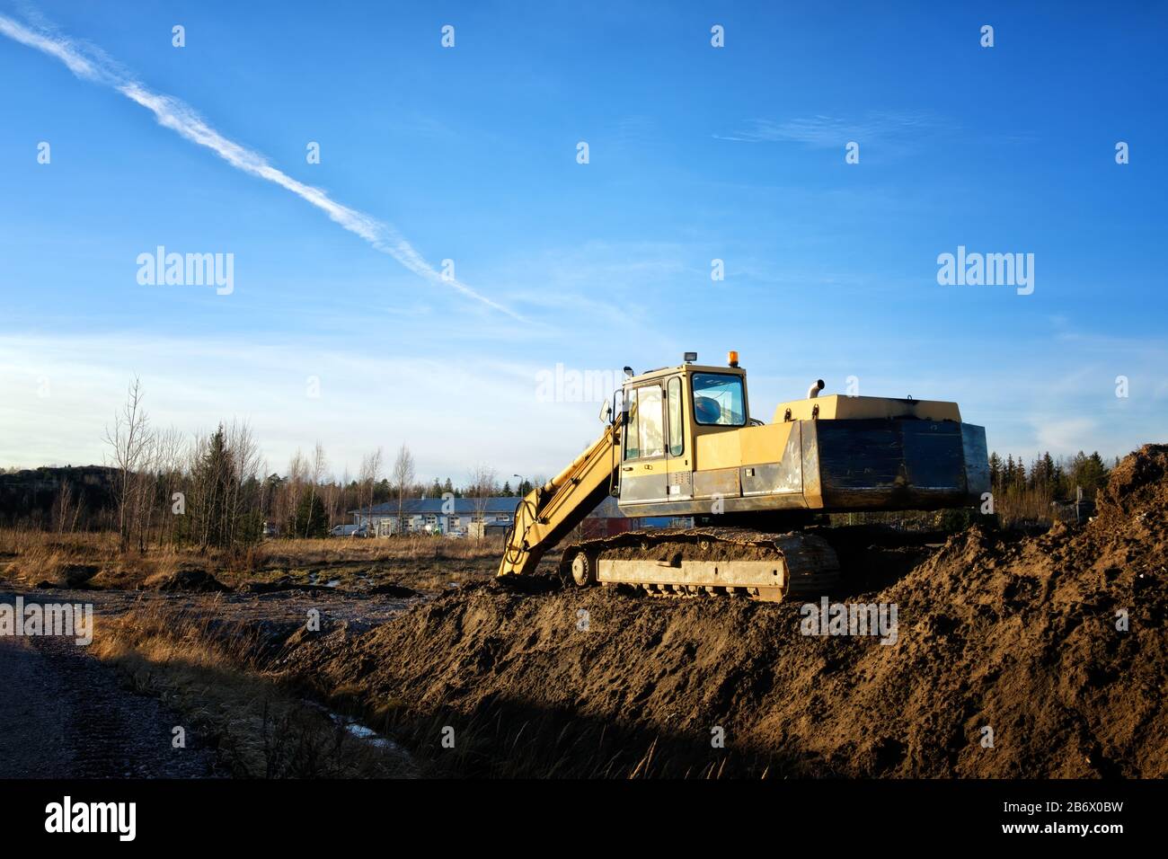 Yellow excavator on a road construction site against blue sky Stock ...