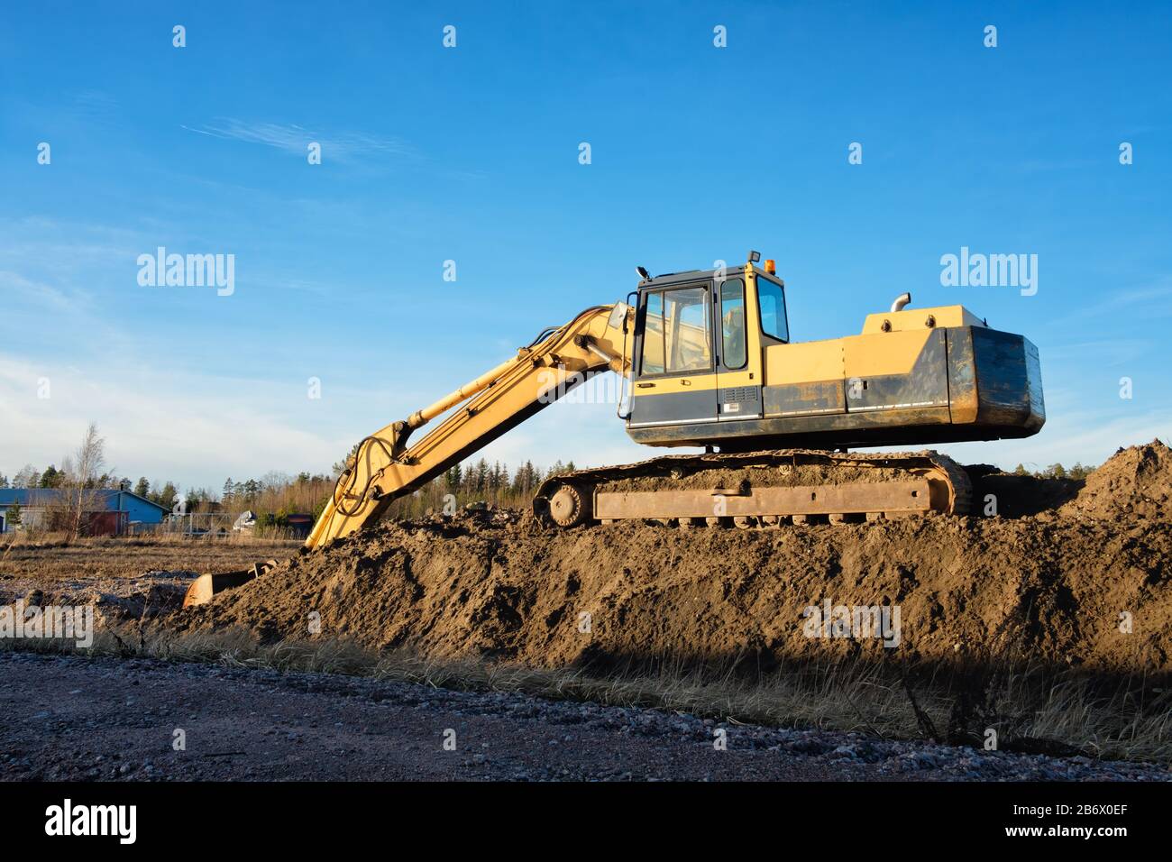 Yellow excavator on a road construction site against blue sky Stock ...