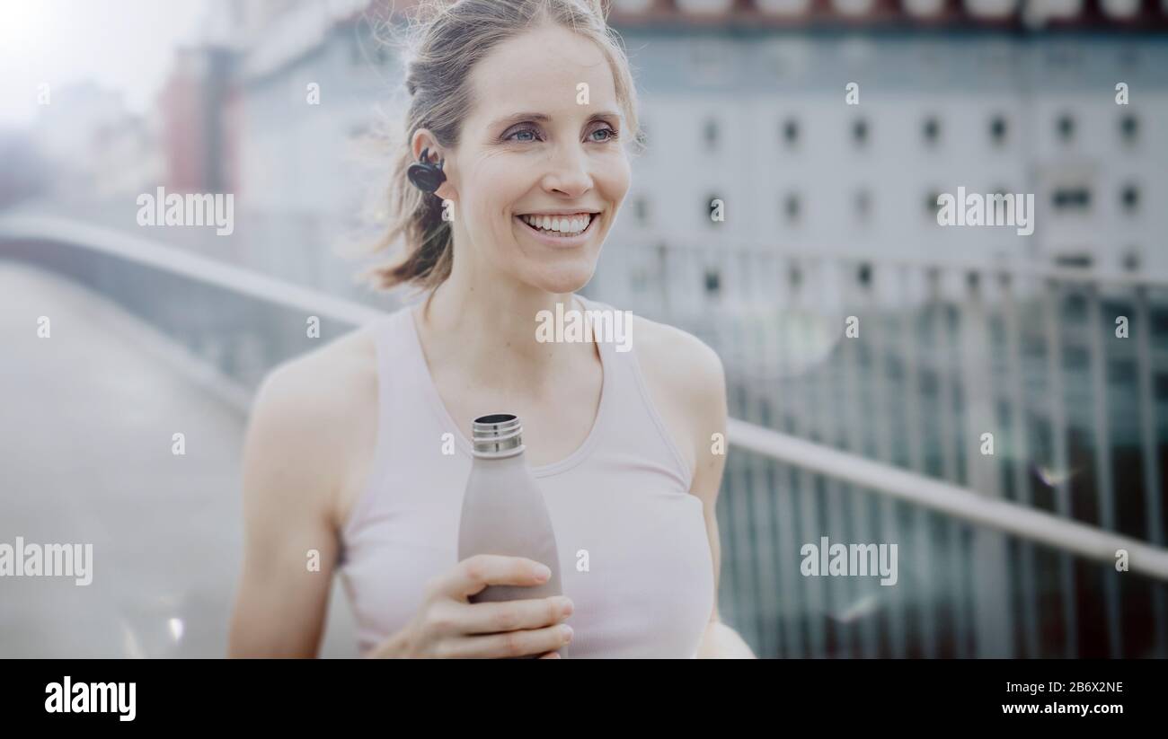 Junge athletische Frau nach dem Joggen mit Wasserflasche in der Hand.Young athletic woman after jogging with water bottle in hand. Stock Photo