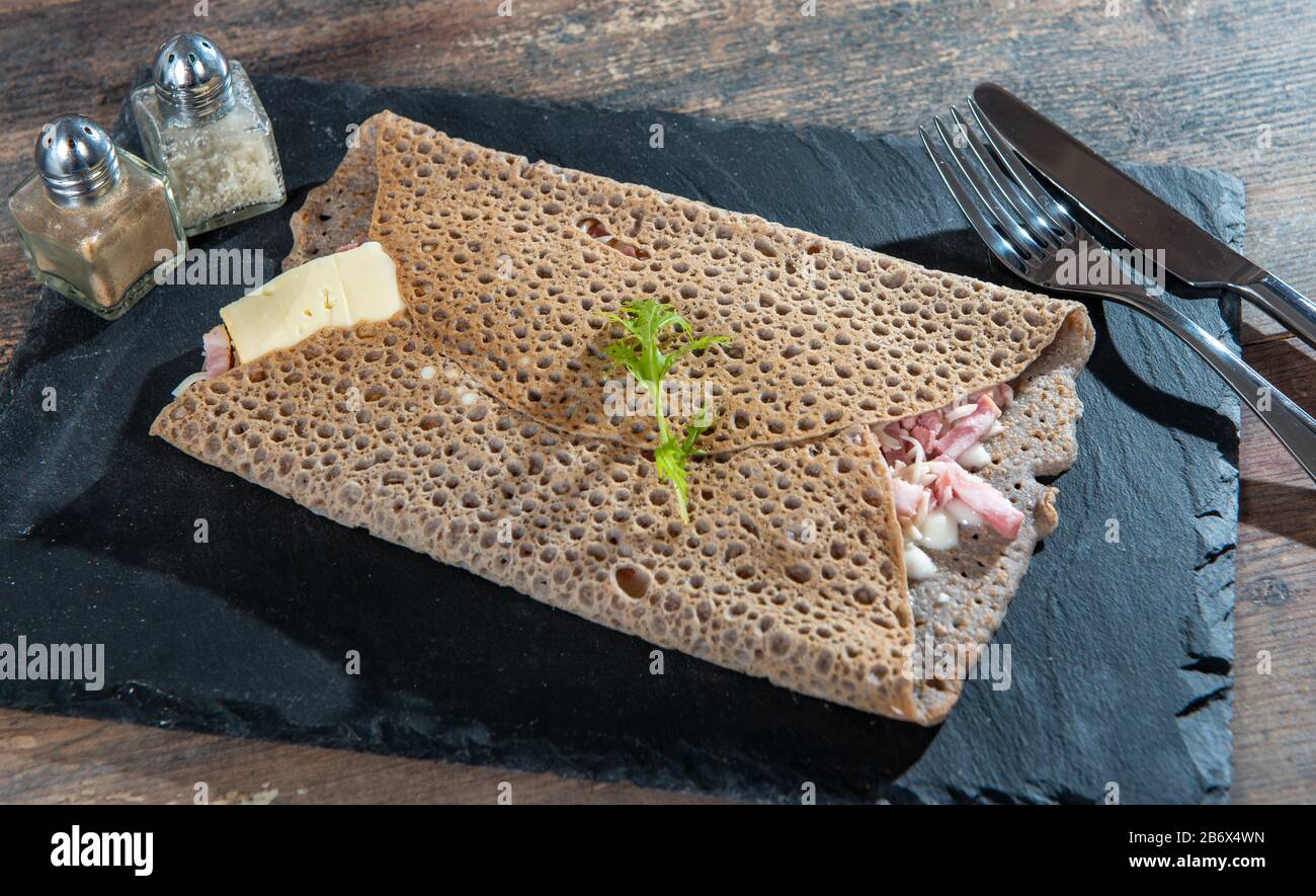Breton crepe with cheese and bacon on a black slate Stock Photo