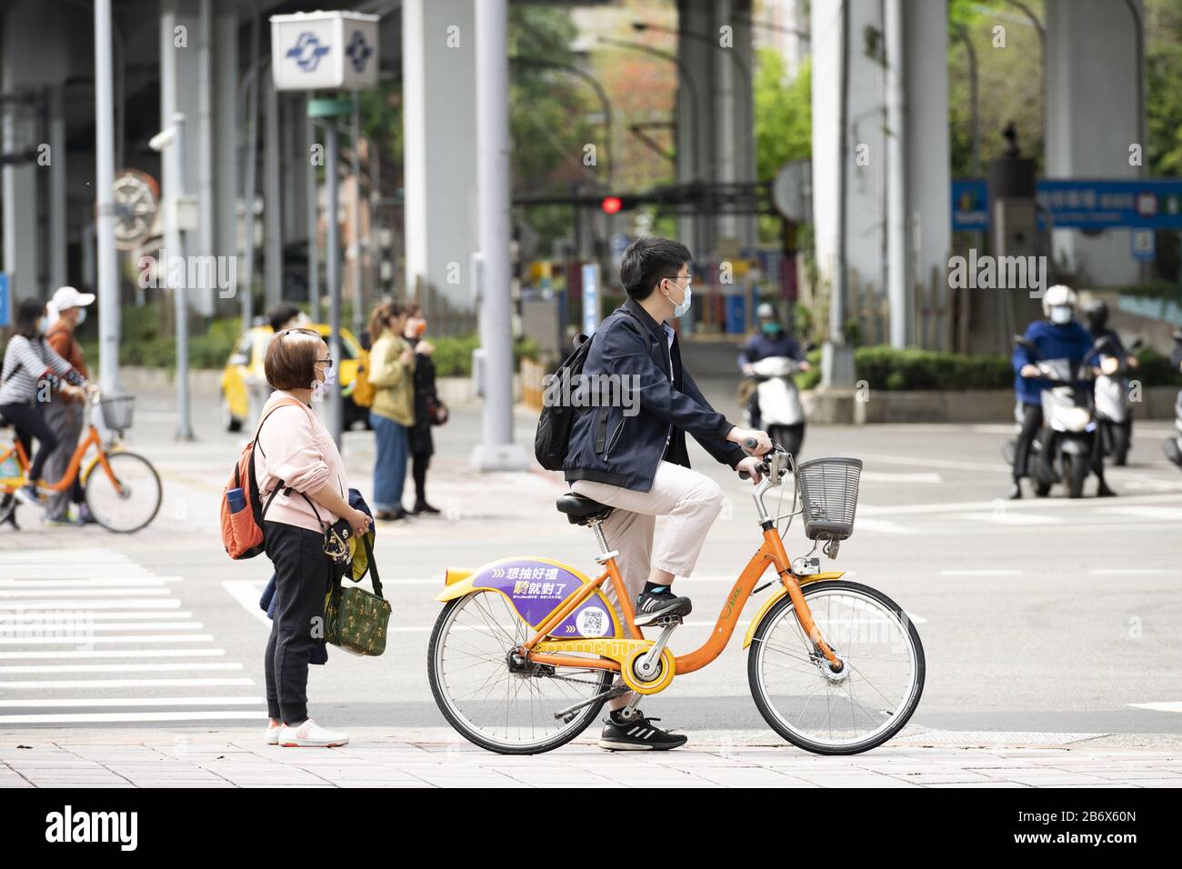 A Taiwanese man, wearing a face mask to protect himself from the novel coronavirus 2019-nCoV or COVID-19 is riding a bike in Taipei, Taiwan. Stock Photo