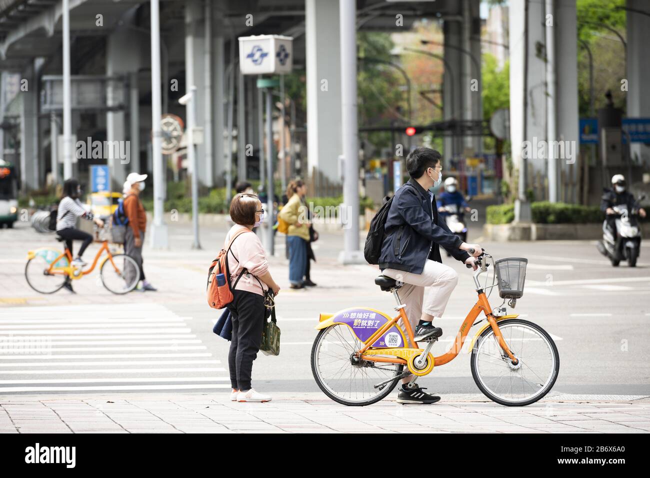 A Taiwanese man, wearing a face mask to protect himself from the novel coronavirus 2019-nCoV or COVID-19 is riding a bike in Taipei, Taiwan. Stock Photo