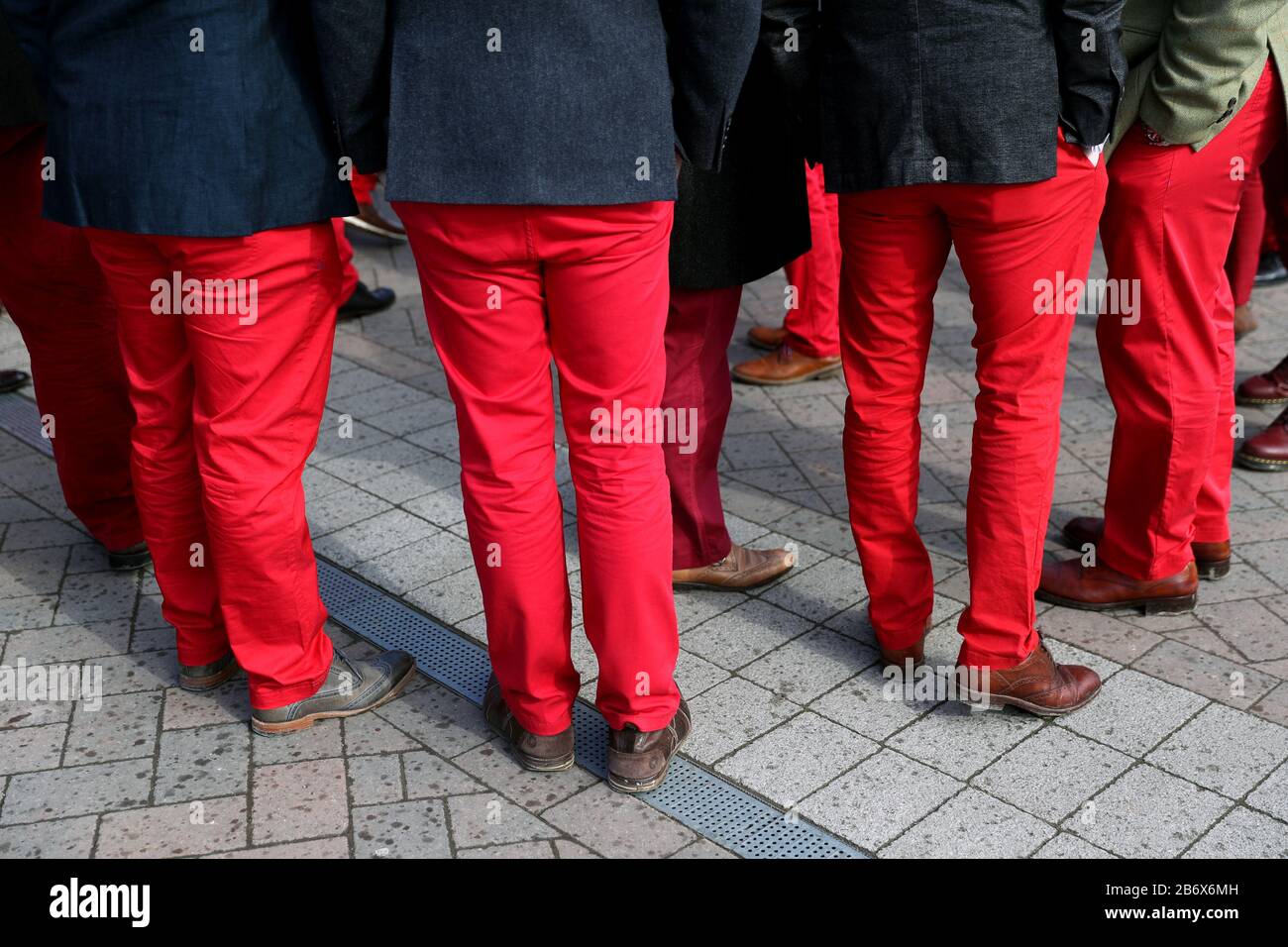 Racegoers in matching red trousers arrive during day three of the Cheltenham Festival at Cheltenham Racecourse. Stock Photo