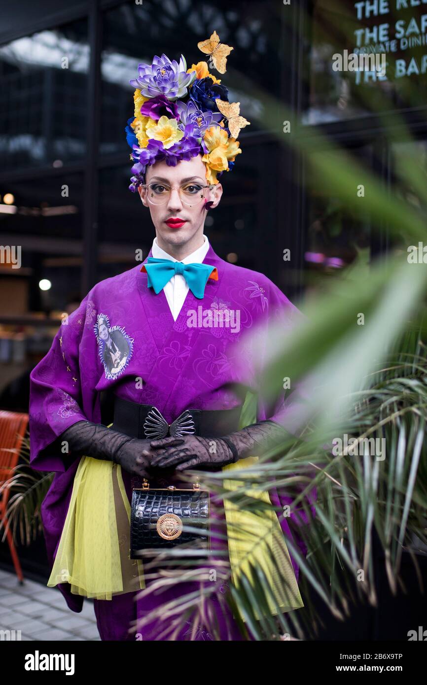 LONDON, UK- febryary 15 2020: Fashionable people on the street . Street style. A man in a purple kimono with a bright make-up and a crown made of yell Stock Photo