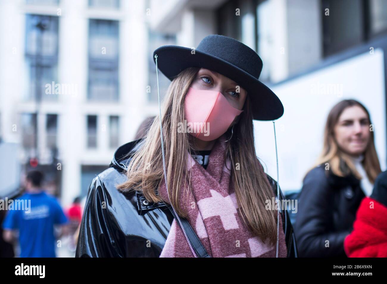 LONDON, UK- febryary 15 2020: Fashionable people on the street . Street style. Woman in a wide-brimmed hat in a pink mask in the era of the coronoviru Stock Photo