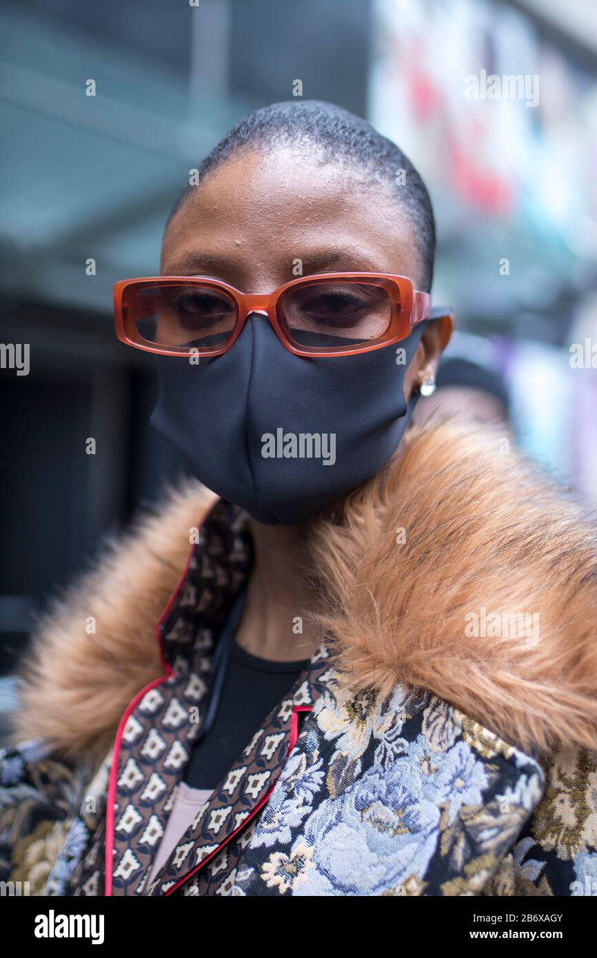 LONDON, UK- febryary 15 2020: Fashionable people on the street . Street style. Girl in a brown suit and medical mask, defends herself from a coronovir Stock Photo