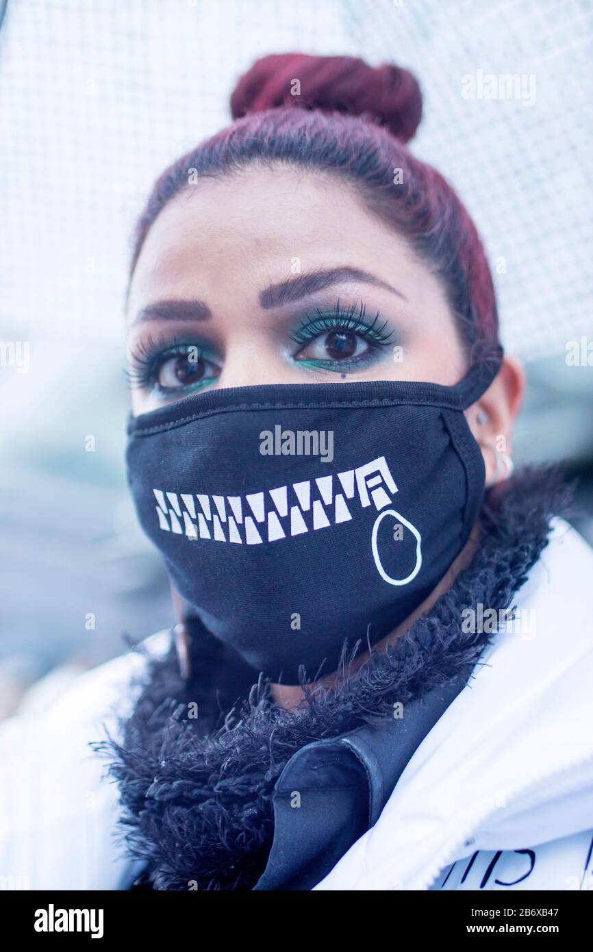 LONDON, UK- febryary 15 2020: Fashionable people on the street . Street style. Young girl in a black medical mask with a painted zipper protects herse Stock Photo