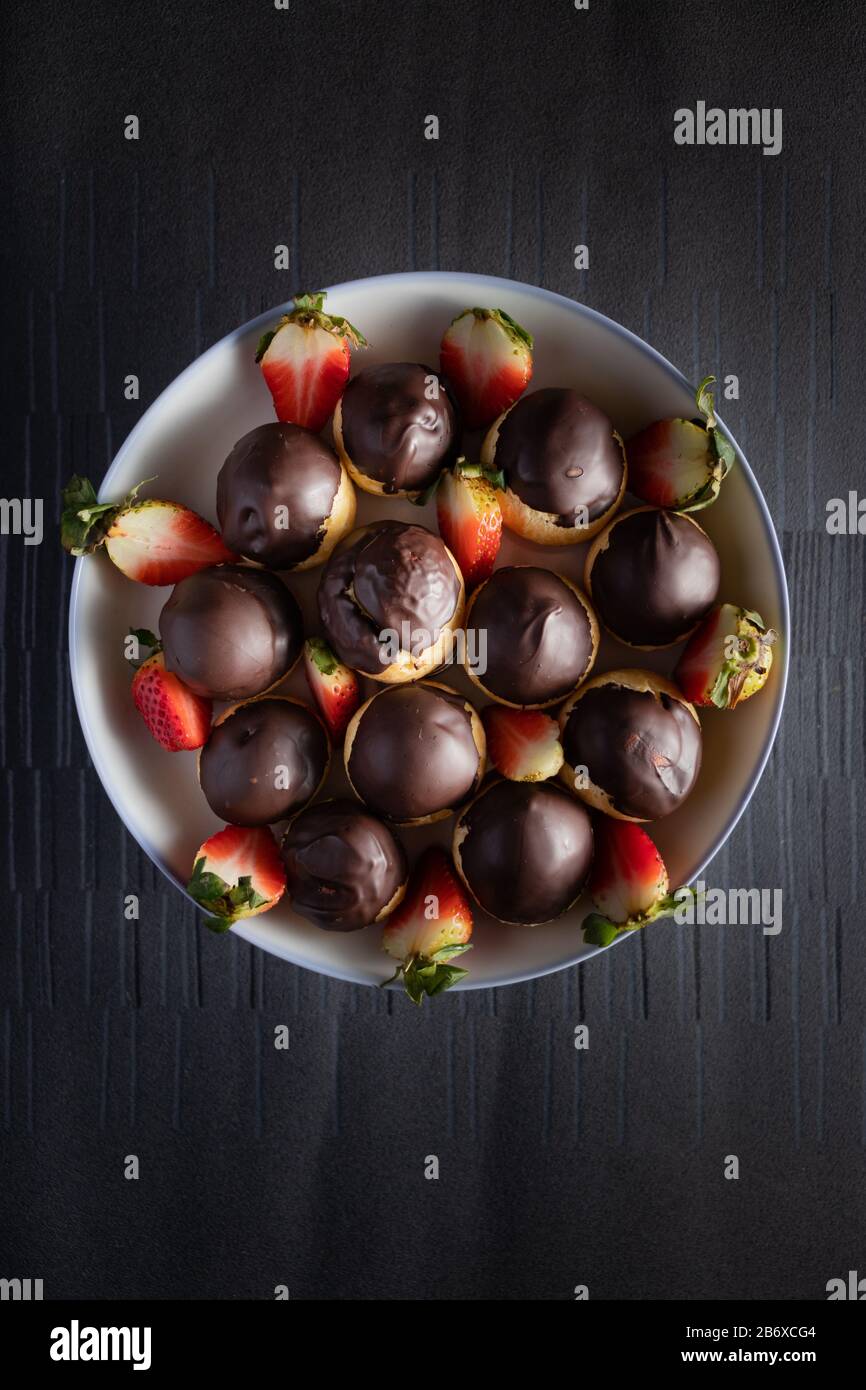 chocolate eclairs with strawberries in dish on a dark background Stock Photo