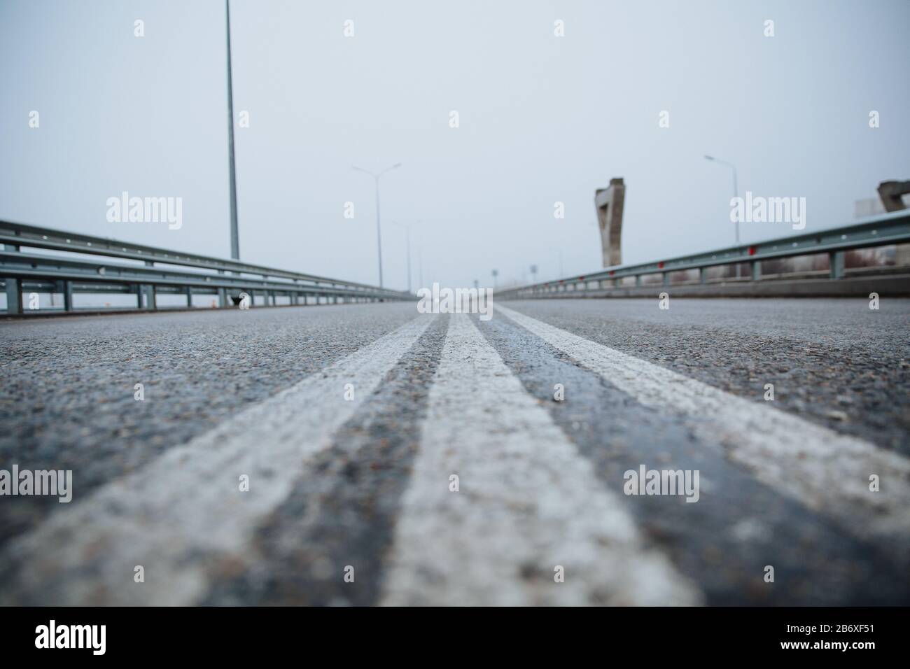 The dividing line on the road is white the view from below on the road paved going. Road markings on asphalt on the street. Stock Photo