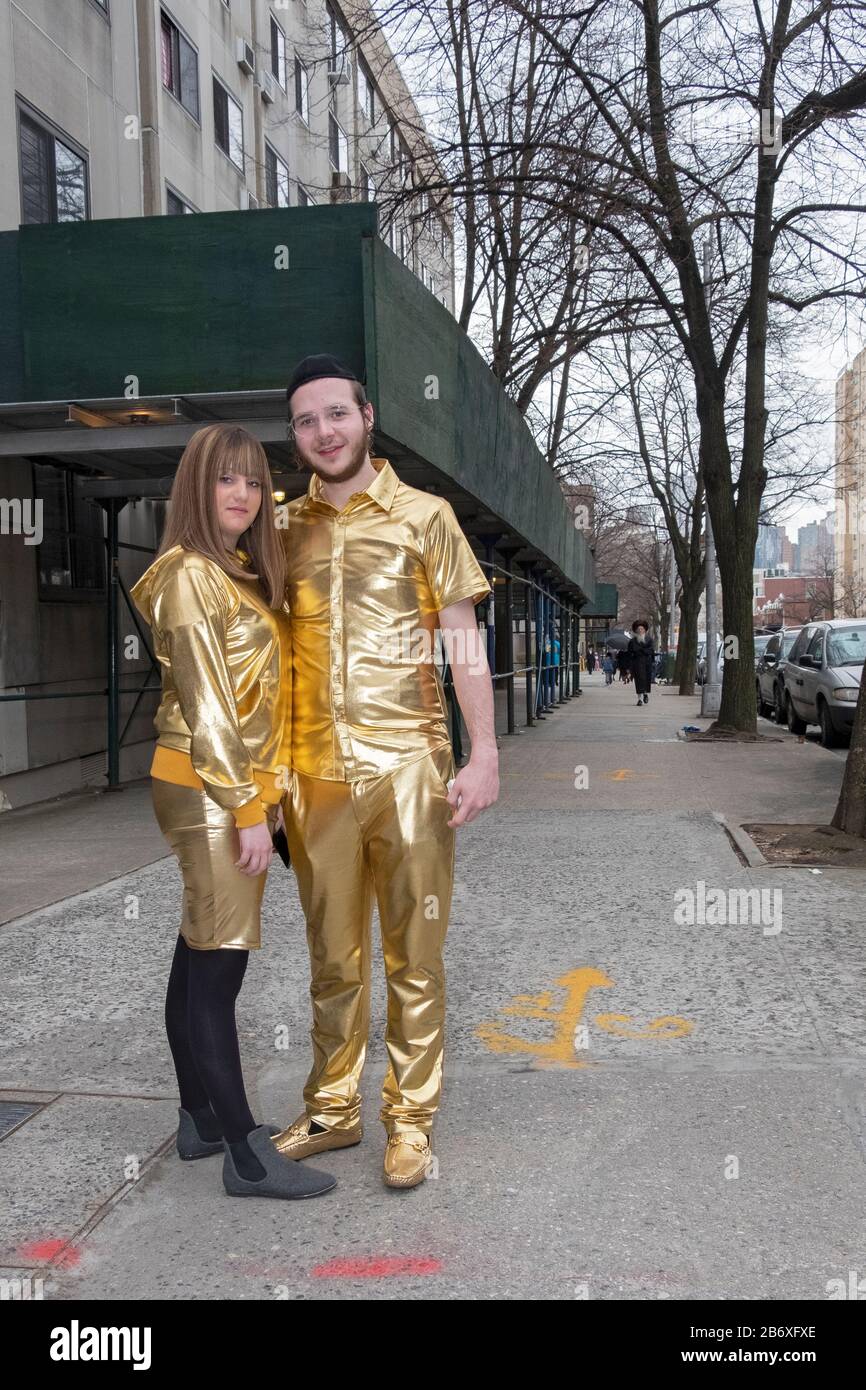 An orthodox Jewish couple wearing gold lame suits as Purim costumes. In Williamsburg, Brooklyn, New York City. Stock Photo