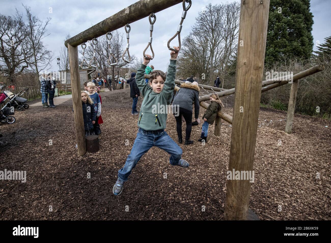 Active boys climbing on the RHS Back to Nature Garden outdoor activity area at RHS Wisley co-designed by The Duchess of Cambridge, Surrey, England, UK Stock Photo