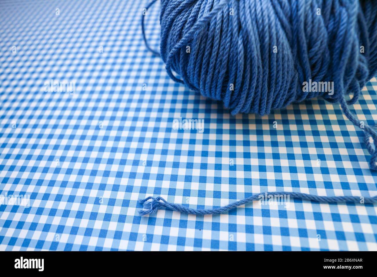 Blue yarn ball on a blue checkered background. Stock Photo