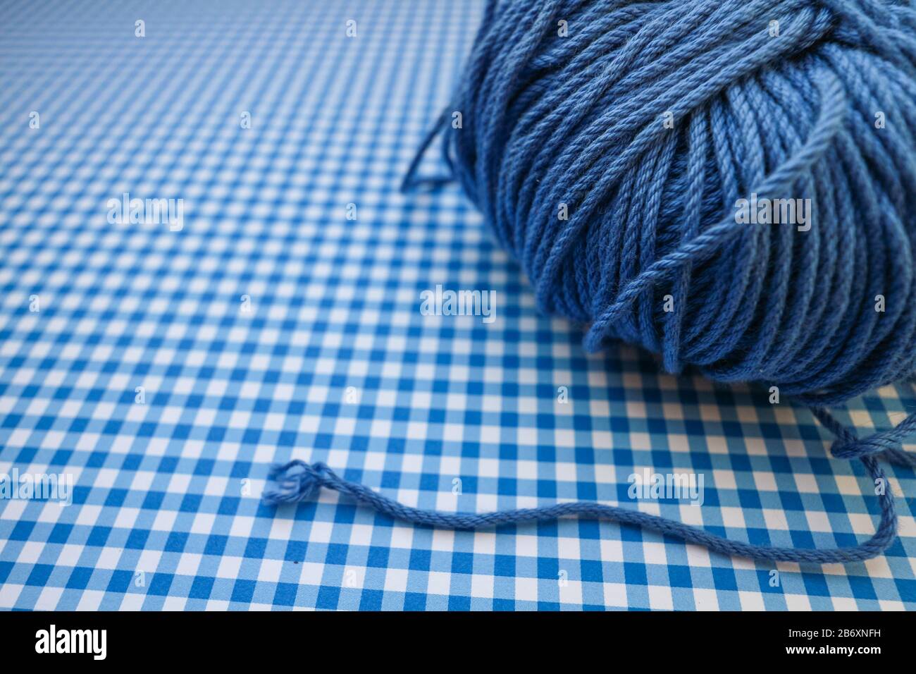 Blue yarn ball on a blue checkered background. Stock Photo