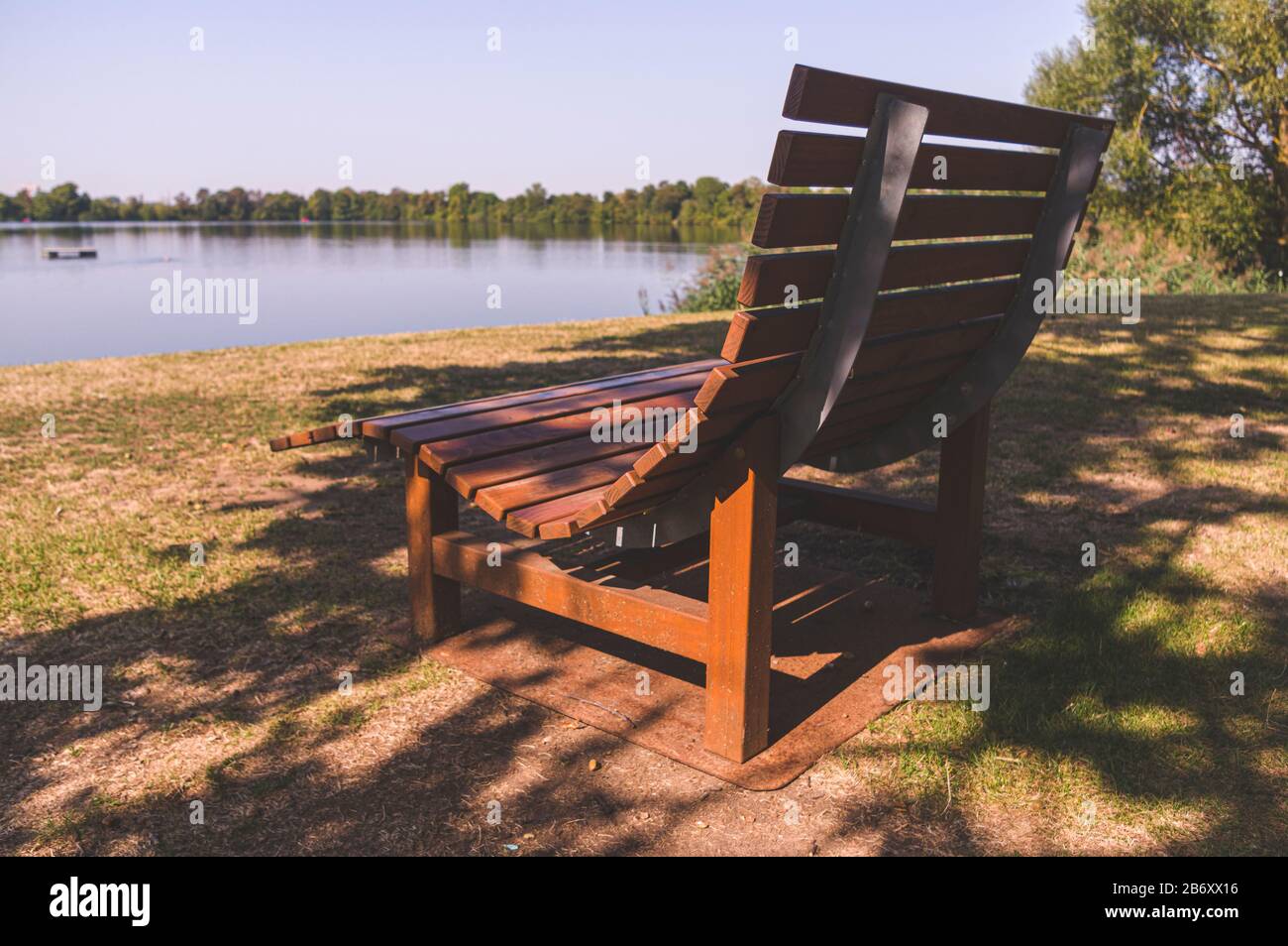 Wooden deck chair on an idyllic bathing lake with a leisure facility