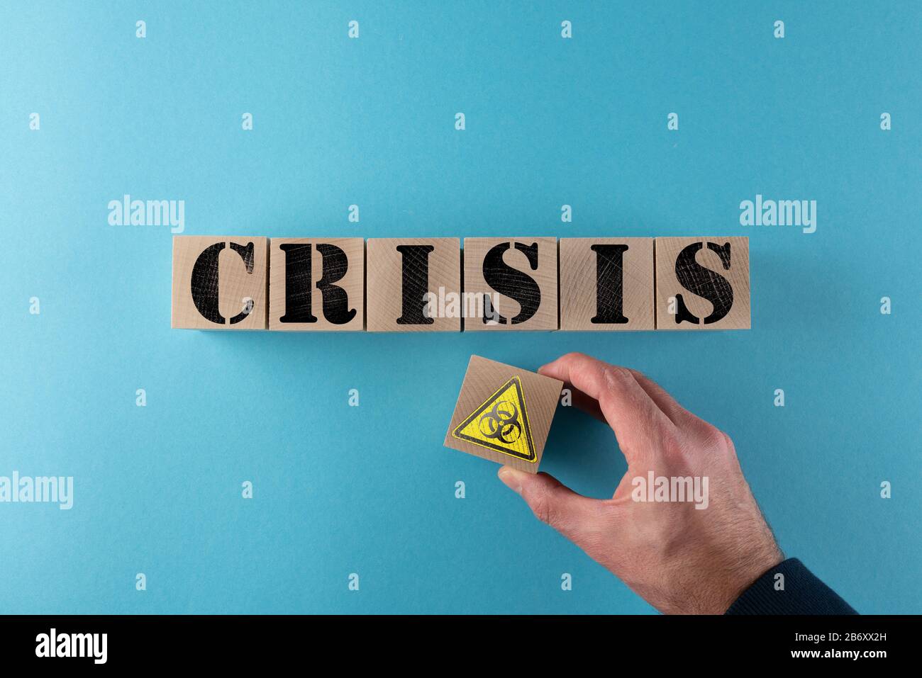 top view of word CRISIS and biohazard warning sign on wood cubes, biological threat and virus crisis concept Stock Photo