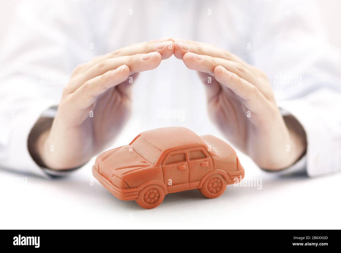 Car insurance concept with orange car toy covered by hands Stock Photo