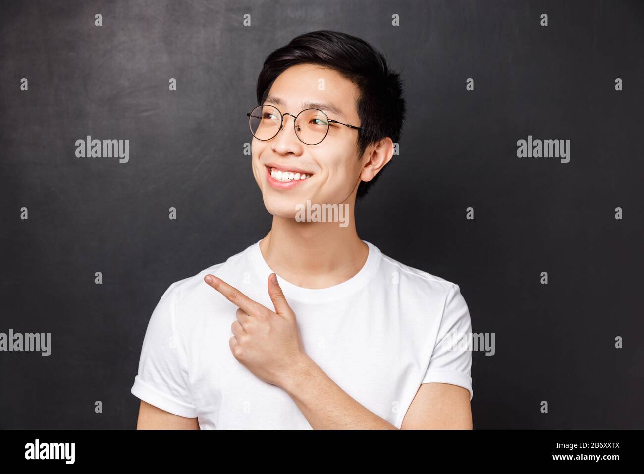 Close up portrait of pleased dreamy cute asian guy in glasses spot something cool pointing and looking upper left corner with satisfied expression Stock Photo Alamy