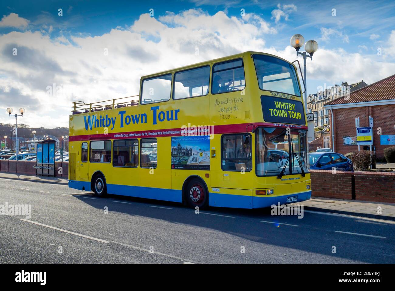 A bright yellow open topped double decker bus which takes tourists on a tour around the seaside town of Whitby Stock Photo