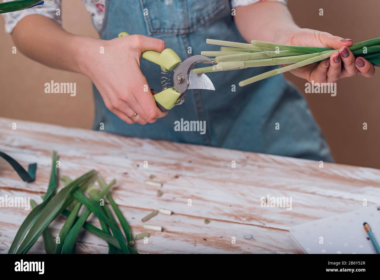 Hands of young woman florist cutting fresh flowers making bouquet of
