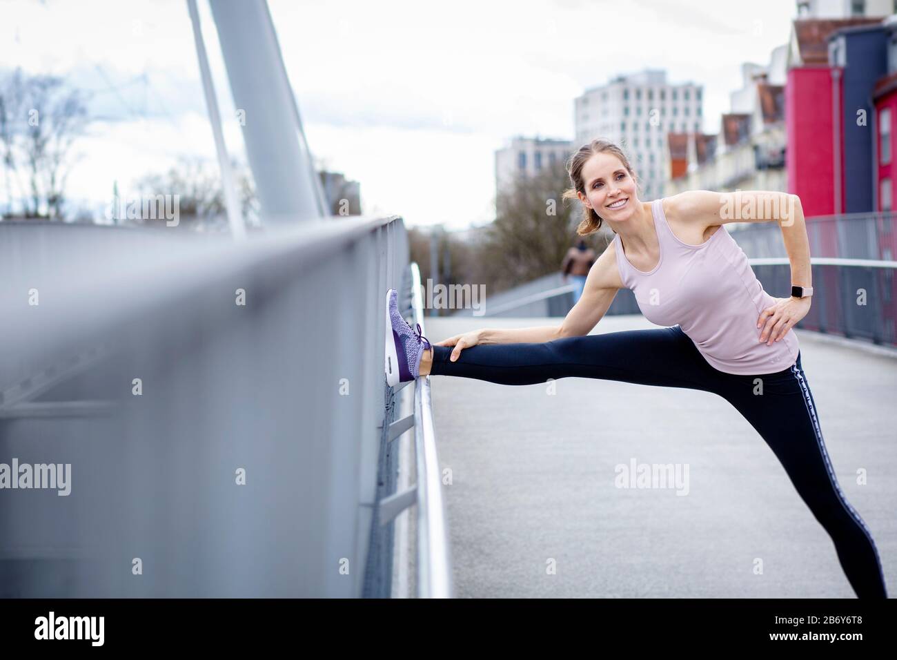 Junge Sportlerin macht Dehnübungen nach dem Sport in der Stadt. Young sportswoman does stretching exercises after sports in the city. Stock Photo