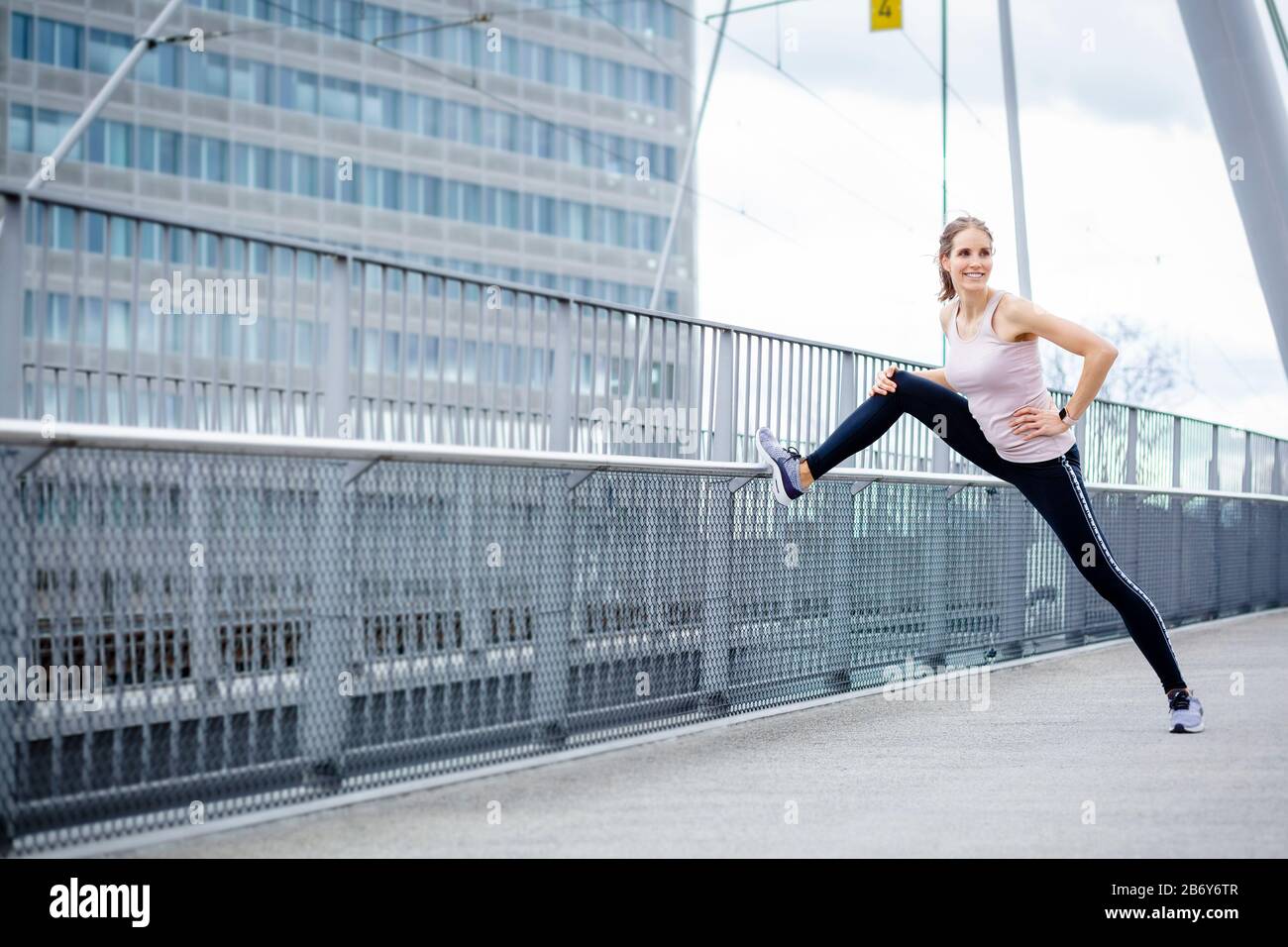 Junge Sportlerin macht Dehnübungen nach dem Sport in der Stadt. Young sportswoman does stretching exercises after sports in the city. Stock Photo