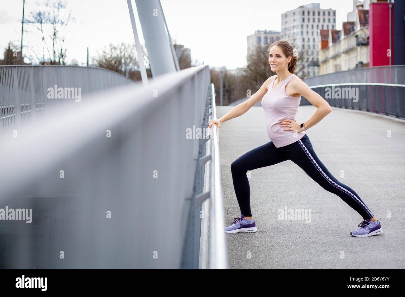 Junge Sportlerin macht Dehnübungen nach dem Sport in der Stadt. Young sportswoman does stretching exercises after sports in the city. Stock Photo