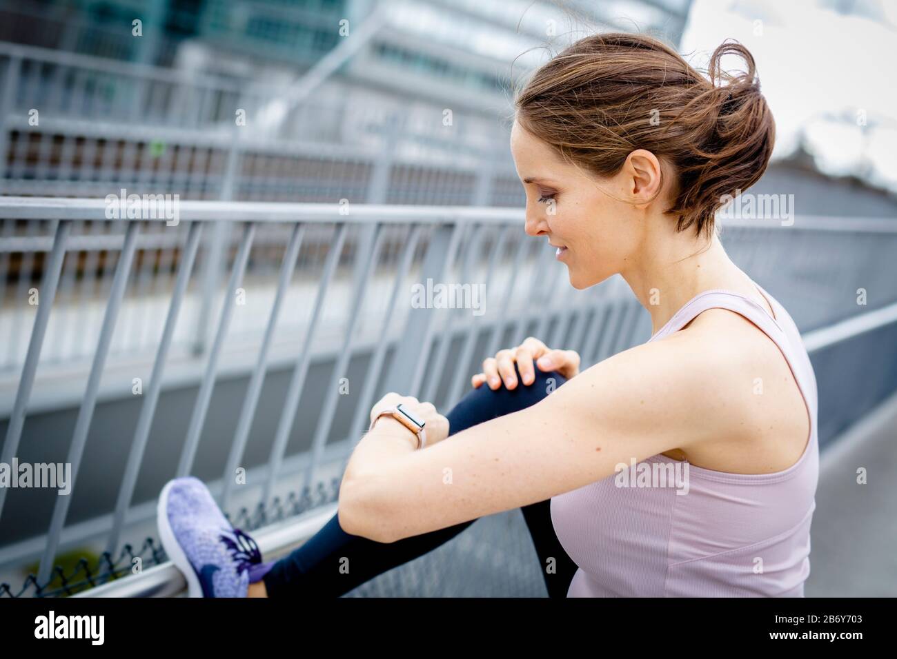 Junge Sportlerin macht Dehnübungen nach dem Sport in der Stadt. Young sportswoman does stretching exercises after sports in the city. Stock Photo