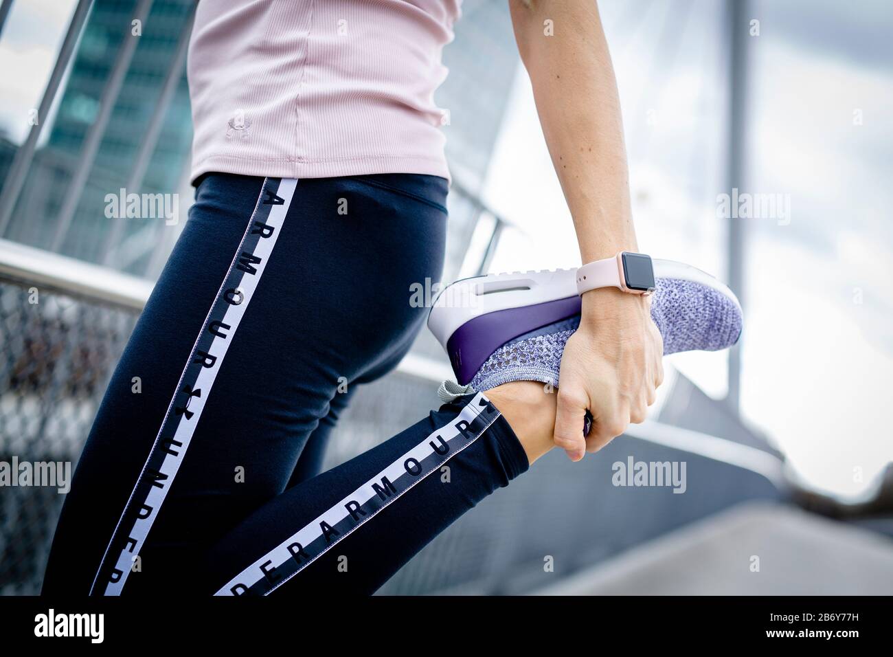 Junge Sportlerin macht Dehnübungen nach dem Sport in der Stadt. Young sportswoman does stretching exercises after sports in the city. Stock Photo