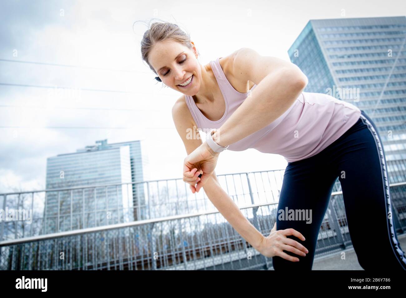 Sportliche Frau fängt ihren Atem nach dem Training während sie ihre Smartwatch überprüft. Female runner taking a break during her jogging. Stock Photo