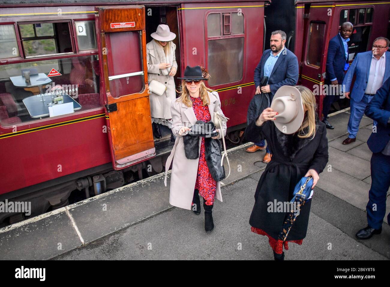 Racegoers make their way onto Cheltenham racecourse after alighting from a vintage train carriage, where people are catching a steam train service to Cheltenham races from Toddington that is running during the festival. Stock Photo