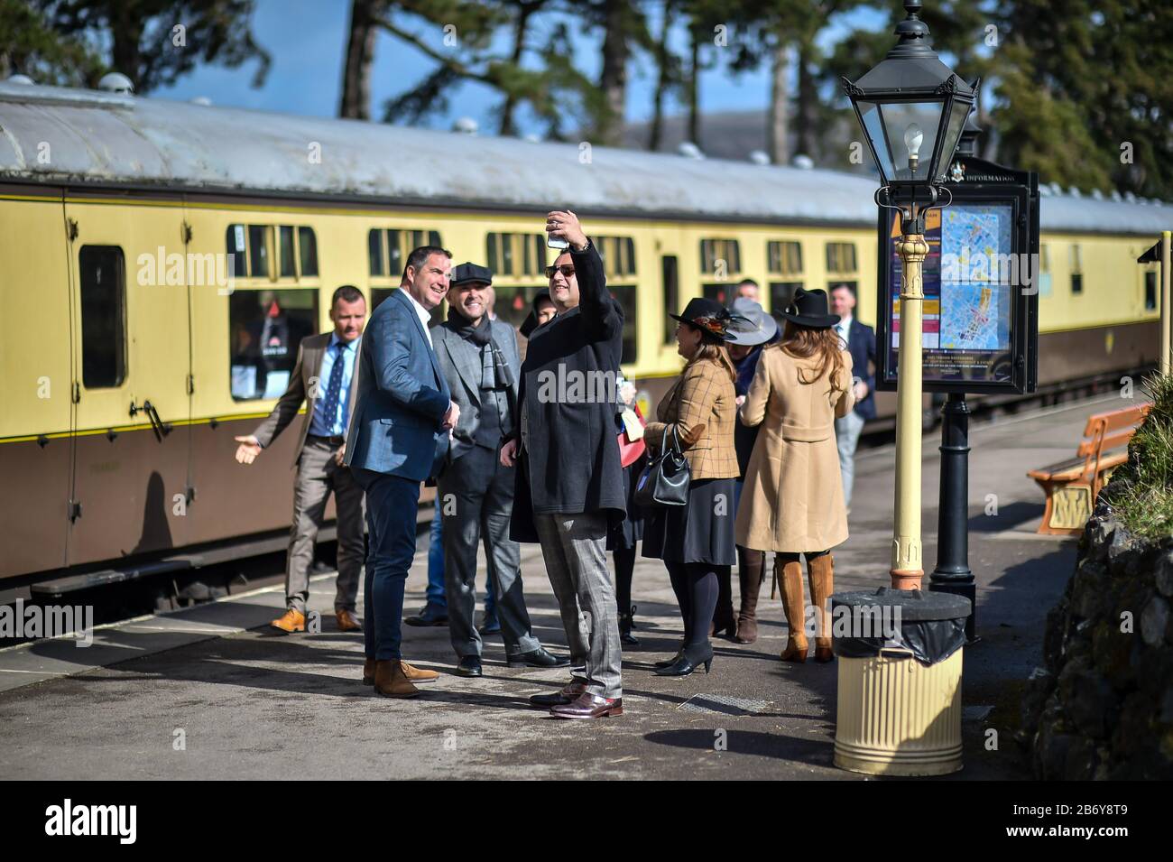 Racegoers make their way onto Cheltenham racecourse after alighting from a vintage train carriage, where people are catching a steam train service to Cheltenham races from Toddington that is running during the festival. Stock Photo