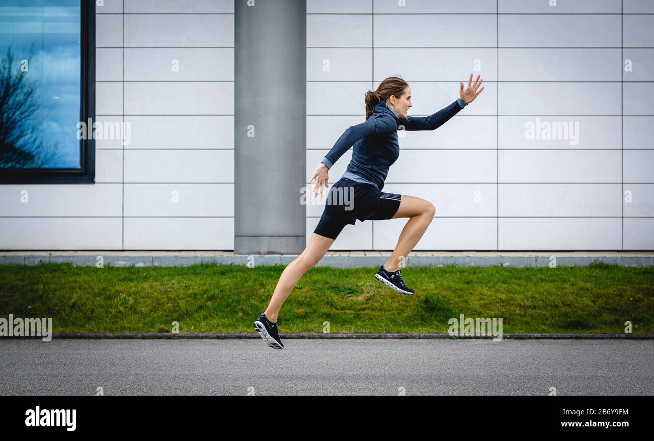 Sportlerin macht Sprintübungen / Startübung für den Sprint draußen in der Stadt. Athletic sportswoman does sprinting exercises outside in the city. Stock Photo