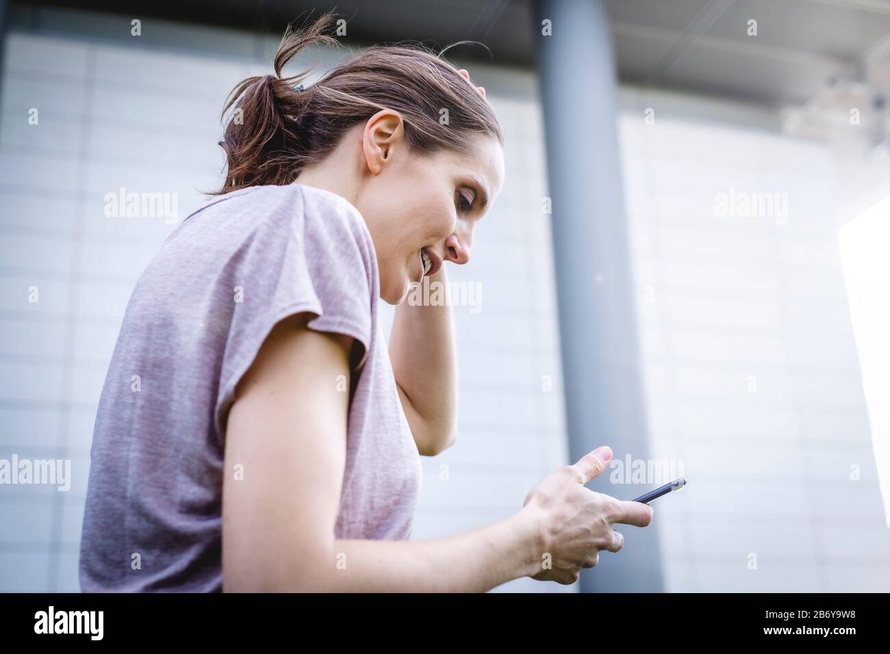 Junge, sportliche Frau macht während des Joggens eine Pause mit Handy in der Hand.  Young, sporty woman takes a break with a cell phone in her hand. Stock Photo