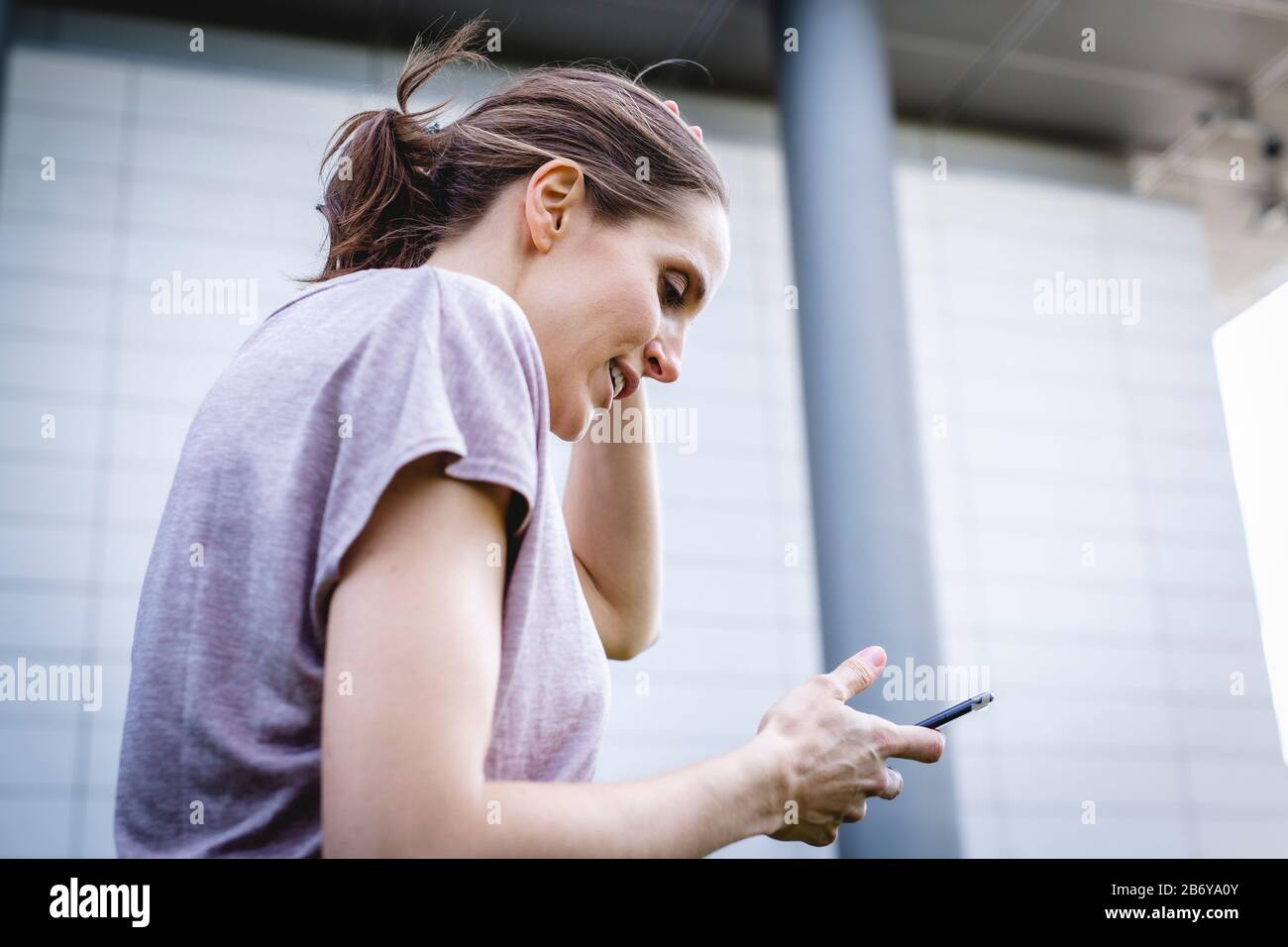 Junge, sportliche Frau macht während des Joggens eine Pause mit Handy in der Hand.  Young, sporty woman takes a break with a cell phone in her hand. Stock Photo